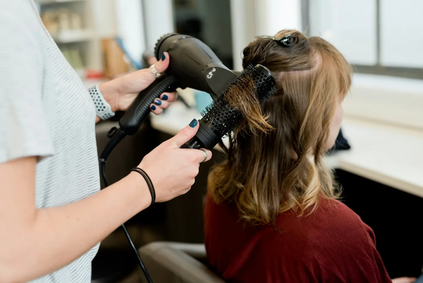 Peluquera secando el pelo a una clienta en el salón