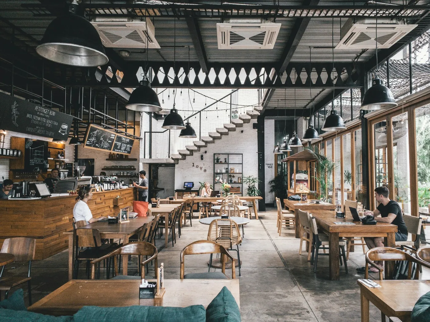 Comedor del restaurante con mesas de madera y cocina abierta al fondo